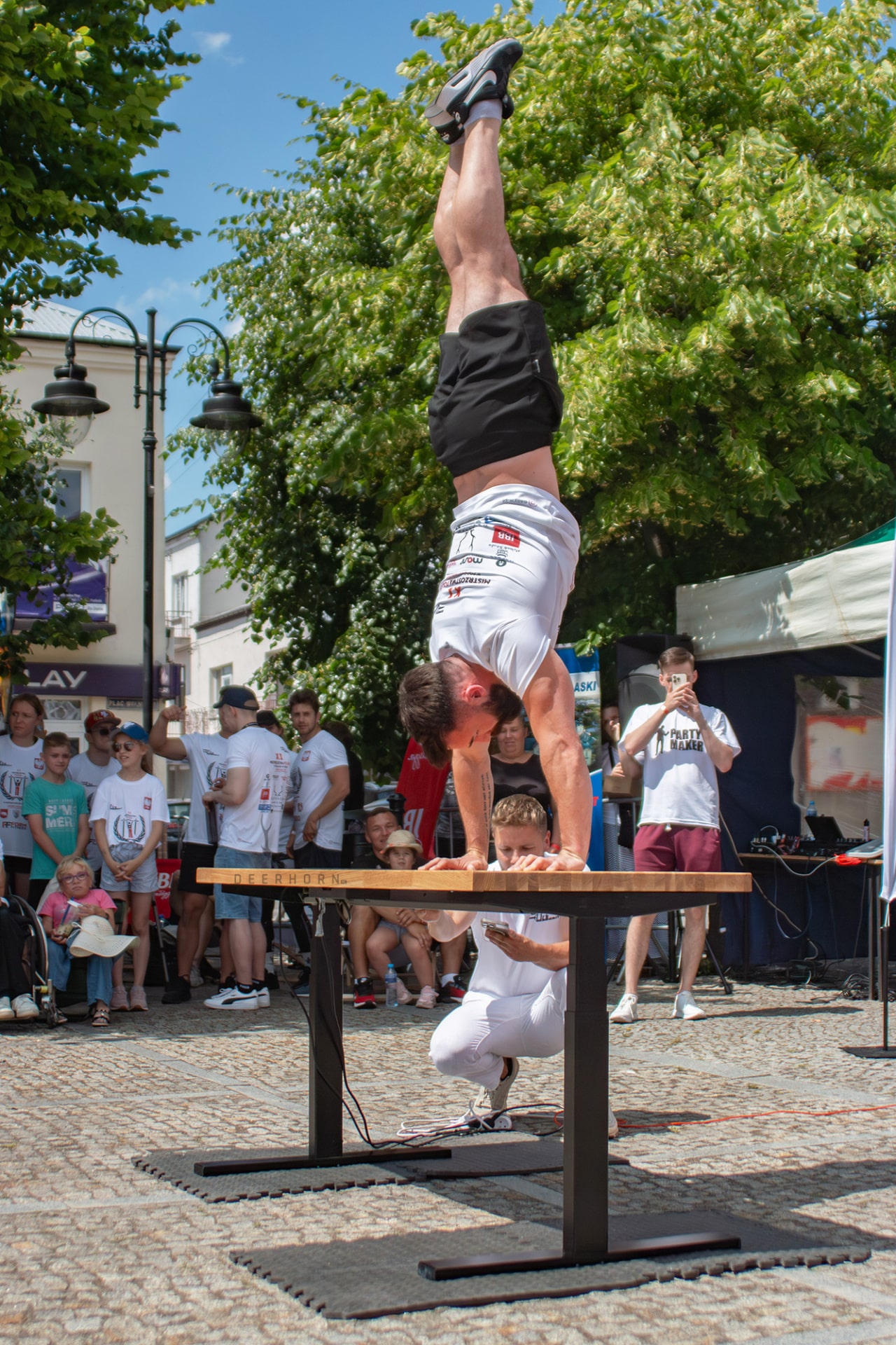 sportovec stojící na rukou na výškově nastavitelném stole