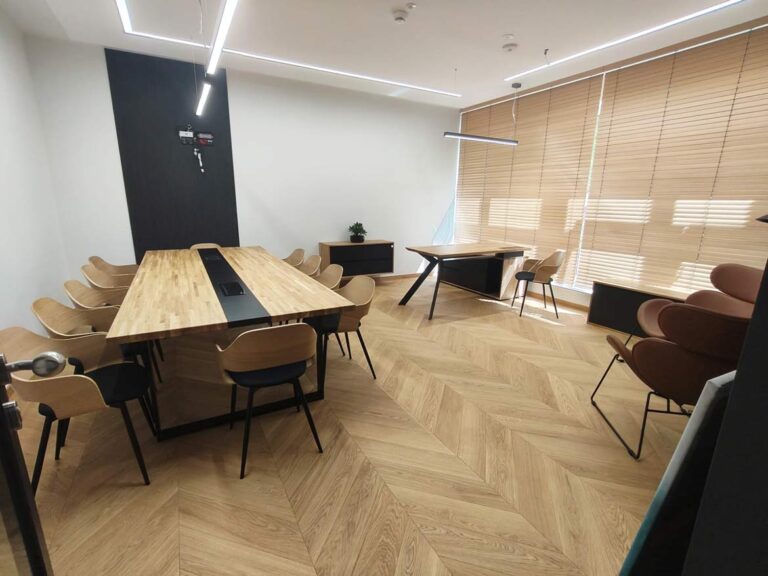 Moderní kancelář s velkým konferenčním stolem a psacím stolem u okna