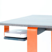 psací stůl s oranžovým podnožím a prostorem pro Mac mini