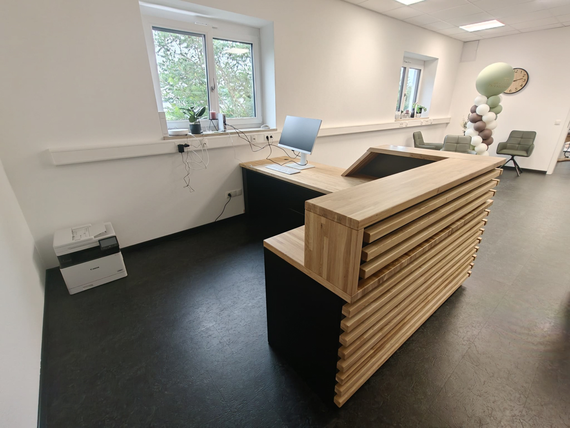 Narożna lada recepcyjna z lamelami dla gabinetu fizjoterapii Heilkunde und Physiotherapie w Ergolding w Niemczech